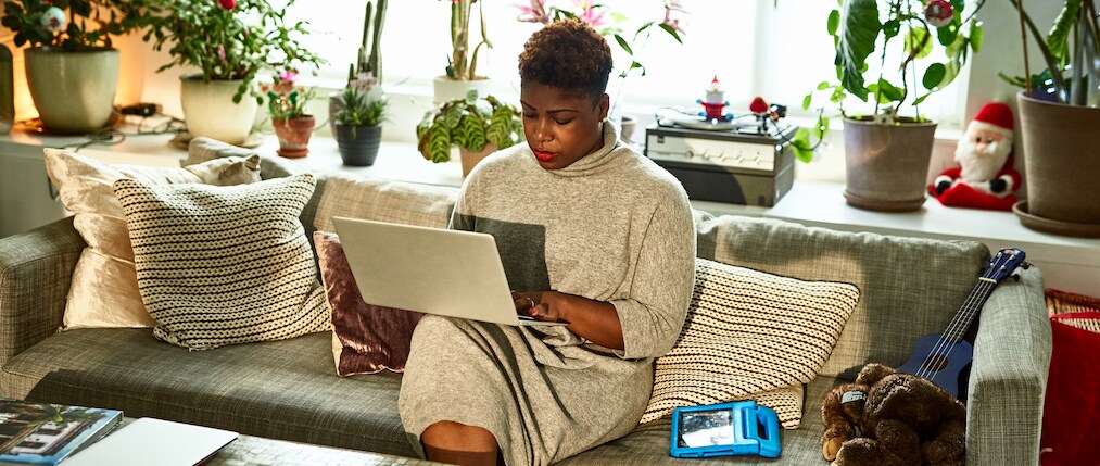 Mid adult woman typing on computer in living room, remote working, freelancer, Christmas season